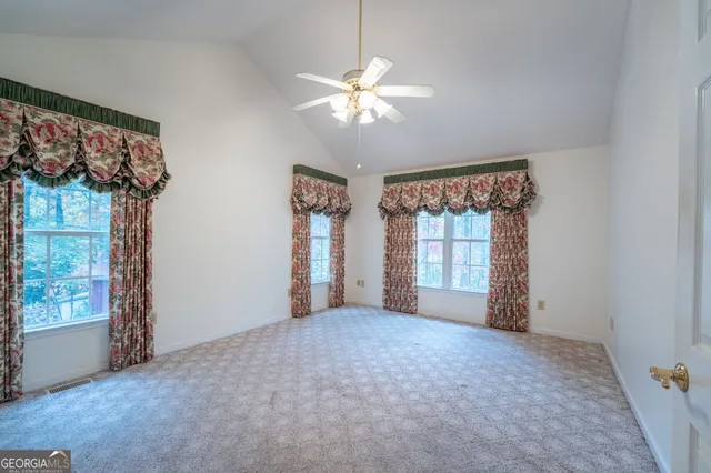 an empty room with a chandelier fan and windows