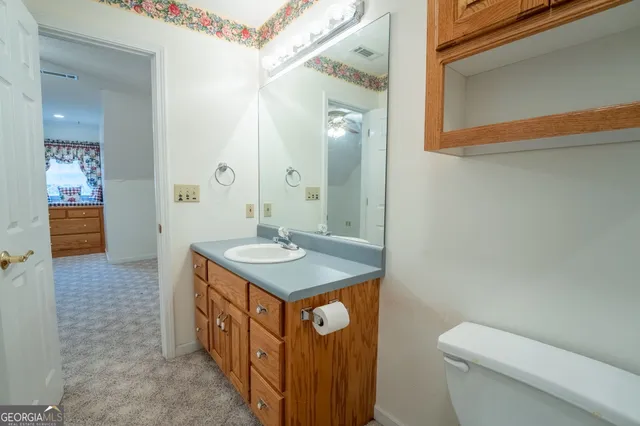a bathroom with a granite countertop sink toilet and a mirror