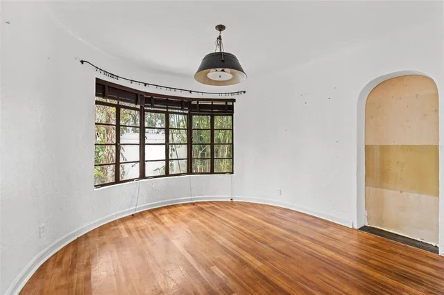 an empty room with wooden floor fan and window