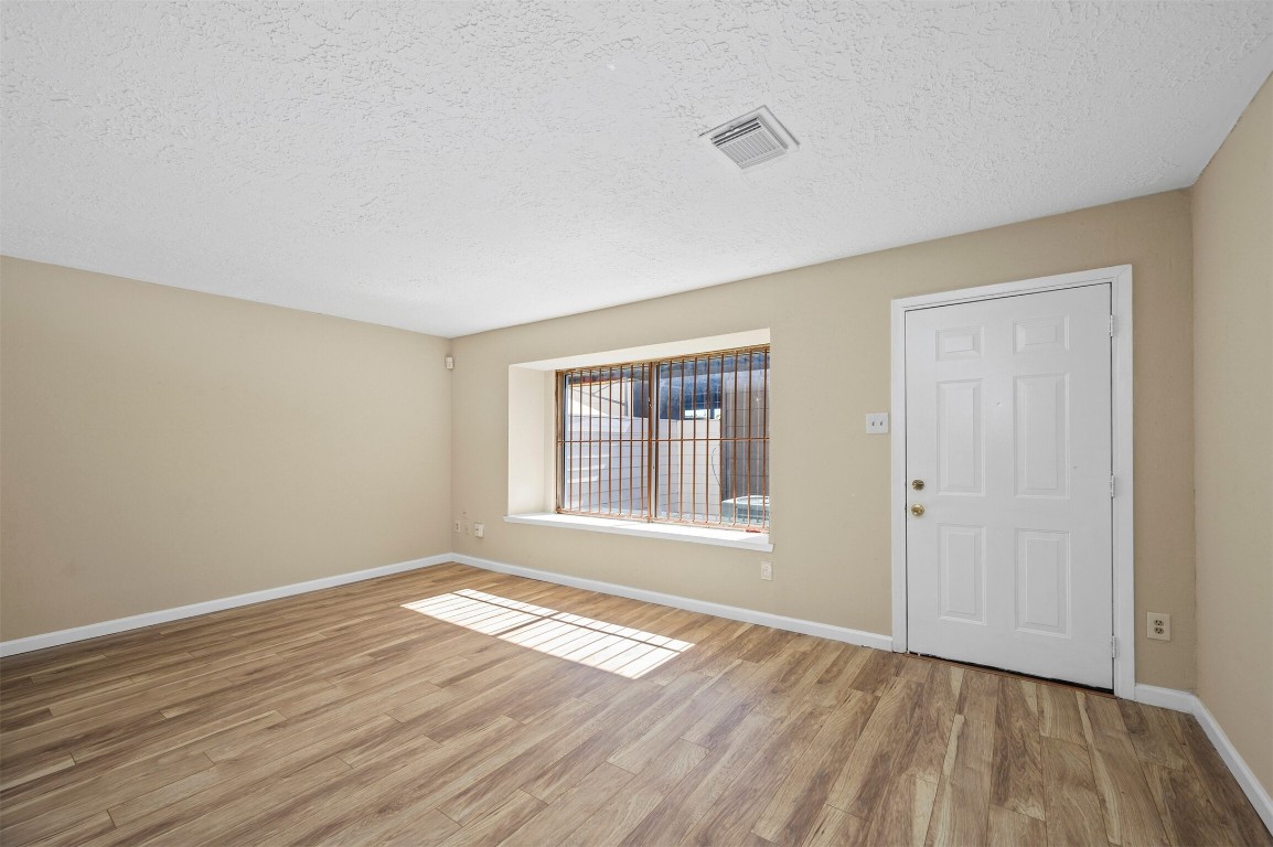 7236 Crownwest Street, Unit 7236 Houston, TX 77072 - Photo 9 of 21 a view of an empty room with wooden floor and a window