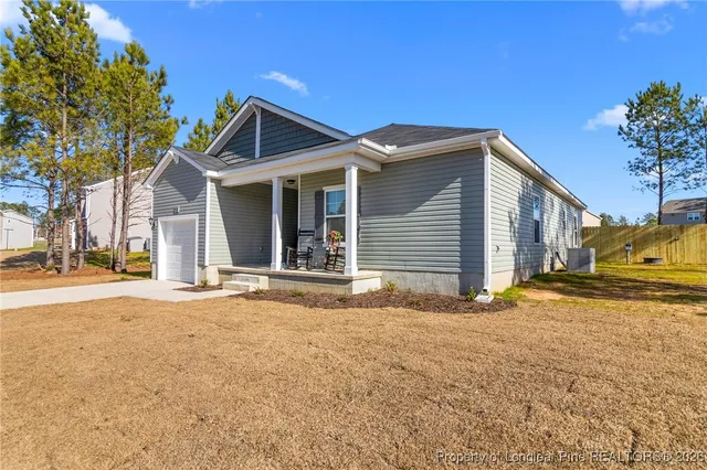 a view of yellow house with a yard and large tree