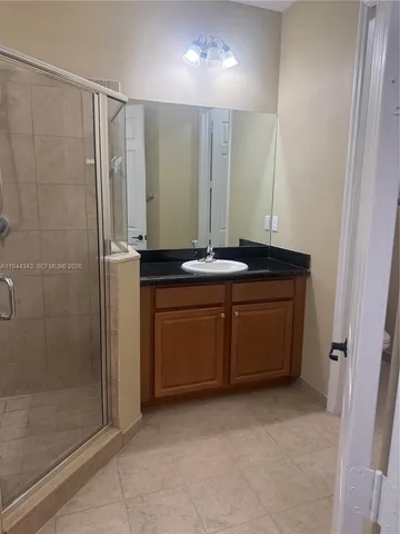 a bathroom with a granite countertop sink a mirror and a shower