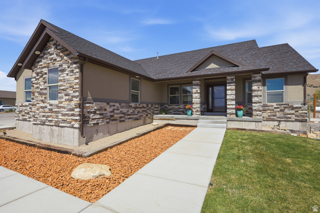 1588 West Rim Rock Drive Stockton, UT 84071 - Photo 46 of 61 Exterior showcasing stacked stone veneer accents, stucco siding, a dark asphalt shingle roof, and a covered entry
