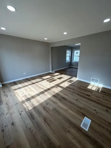 a view of empty room with window and wooden floor