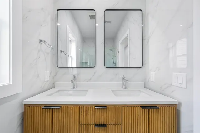a bathroom with double vanity sink and two mirror