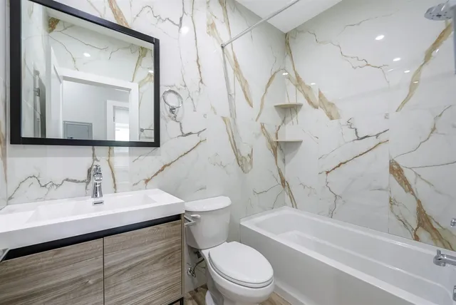 a bathroom with a sink a toilet a mirror and shower