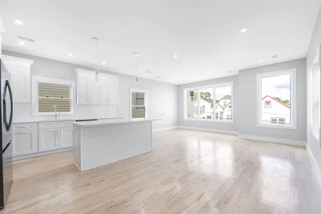 a large white kitchen with wooden floors and view living room