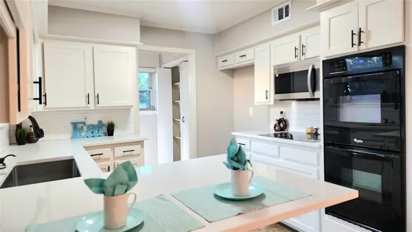 a kitchen with stainless steel appliances kitchen island granite countertop a refrigerator a stove a sink a dining table and chairs