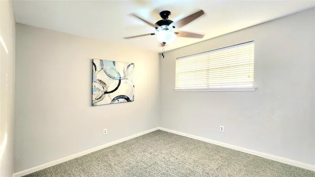 an empty room with a window and a chandelier fan