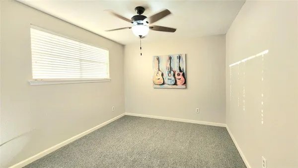 an empty room with a window and a fan