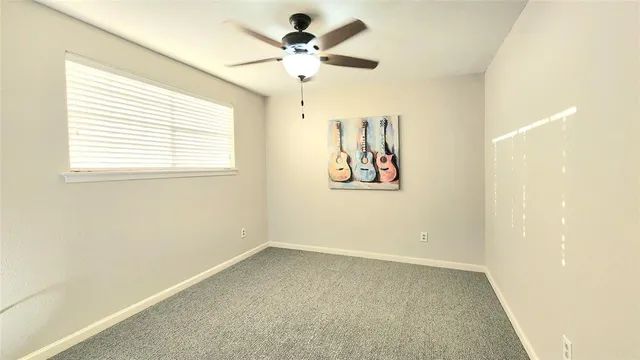 an empty room with a window and a fan