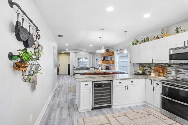 a kitchen with stainless steel appliances kitchen island granite countertop a stove a sink and a white cabinets