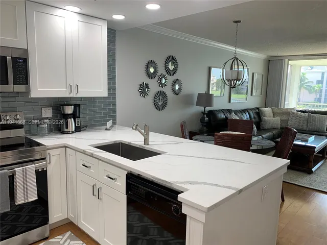 a kitchen with a sink dishwasher a stove top oven a dining table and chairs with wooden floor