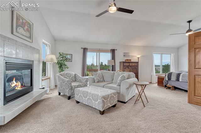 2690 Spaatz Road Monument, CO 80132 - Photo 16 of 50 Carpeted living room featuring ceiling fan, vaulted ceiling, and a tiled fireplace