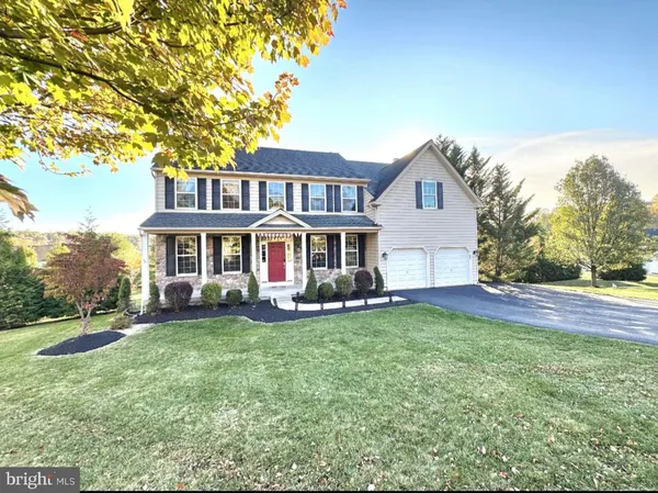 a front view of a house with a garden and trees