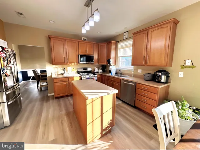 a kitchen with a refrigerator a stove top oven a sink dishwasher and cabinets with wooden floor