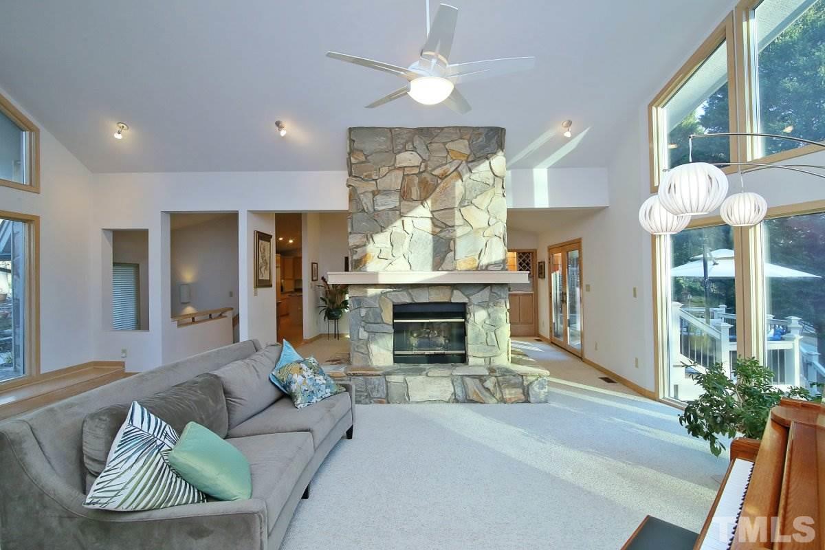 7209 Rainwater Road Raleigh, NC 27615 - Photo 5 of 25 a living room with furniture a fireplace and a chandelier