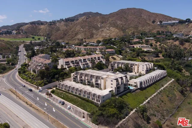 a view of a house with a garden and mountains