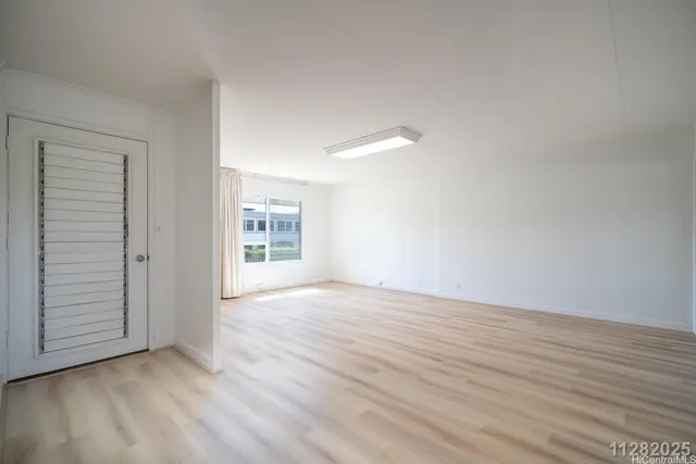 a view of empty room with kitchen and window