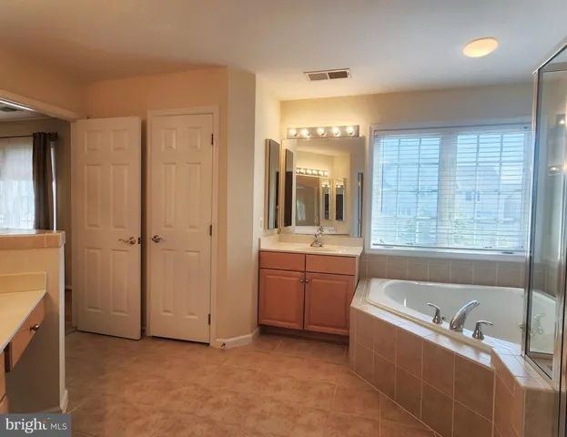 a bathroom with a granite countertop tub sink shower and mirror