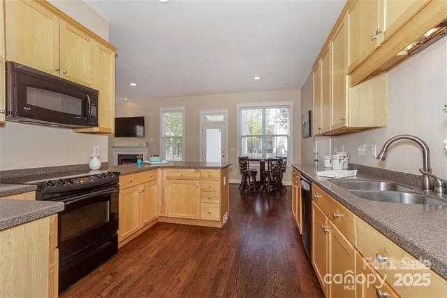 a kitchen with stainless steel appliances a stove a sink a microwave and wooden floors
