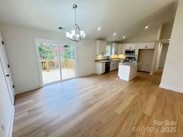 a view of a kitchen with granite countertop wooden floor a refrigerator and a sink