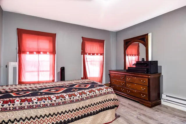 a bedroom with a bed and a dresser with wooden floor