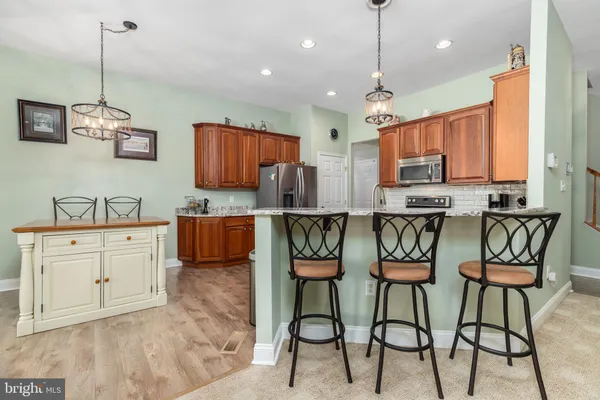 a kitchen with stainless steel appliances kitchen island granite countertop a stove a sink and a refrigerator