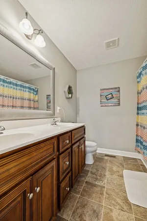 a spacious bathroom with a granite countertop sink a toilet a mirror and bathtub