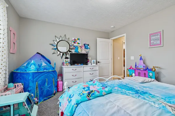 a bedroom with a bed a flat screen tv and dresser
