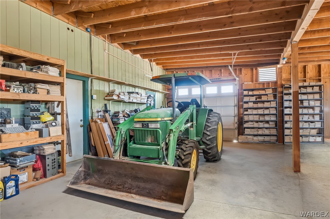 2401 North Stephan Road Kingman, AZ 86401 - Photo 78 of 92 Spacious utility building featuring exposed wood beam ceilings, concrete flooring, overhead garage door, built-in shelving, and a separate entry door