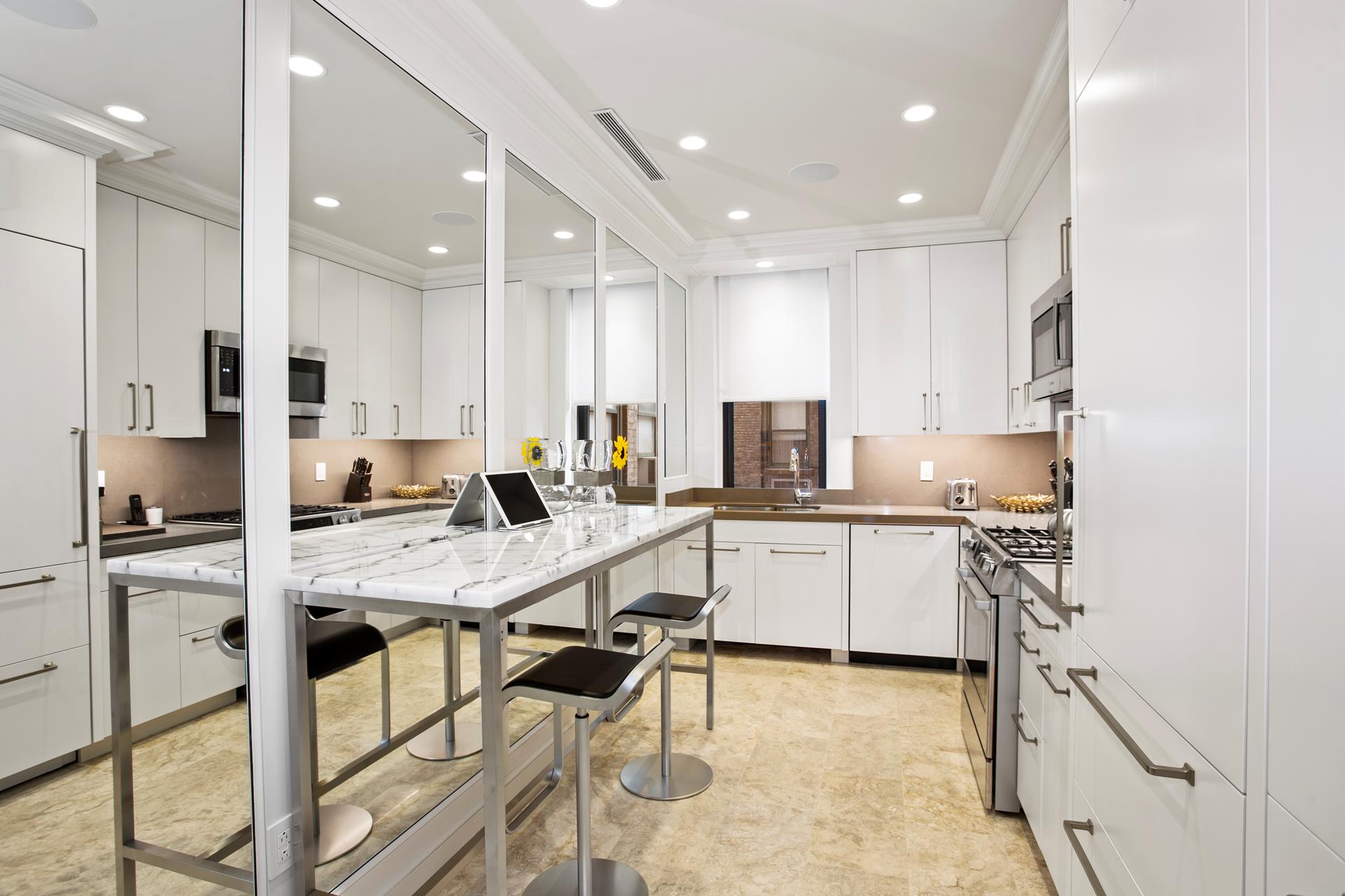 781 5th Avenue, Unit 1101 Manhattan, NY 10022 - Photo 9 of 10 a kitchen with white cabinets and stainless steel appliances