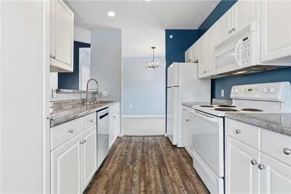 a kitchen with granite countertop white cabinets and white appliances