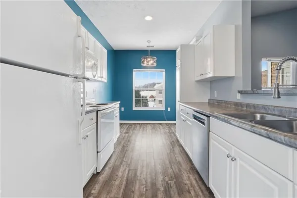 a kitchen with granite countertop a sink cabinets and stainless steel appliances