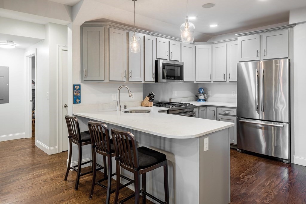 177 Winthrop Road, Unit 1 Brookline, MA 02445 - Photo 2 of 9 a kitchen with stainless steel appliances a white refrigerator a sink a stove a dining table and chairs