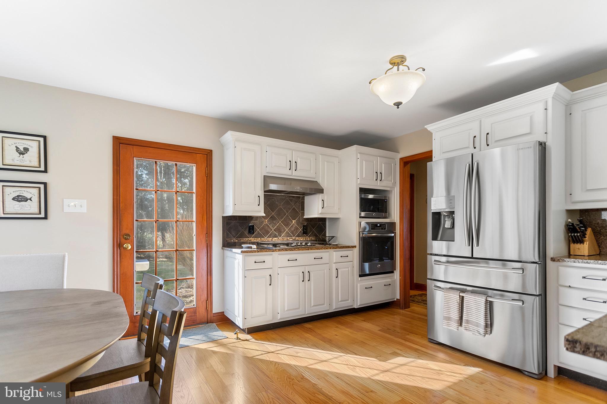 1310 Stackhouse Mill Road Newtown Square, PA 19073 - Photo 11 of 40 a kitchen with stainless steel appliances granite countertop a refrigerator a stove a sink dishwasher a dining table and chairs with wooden floor