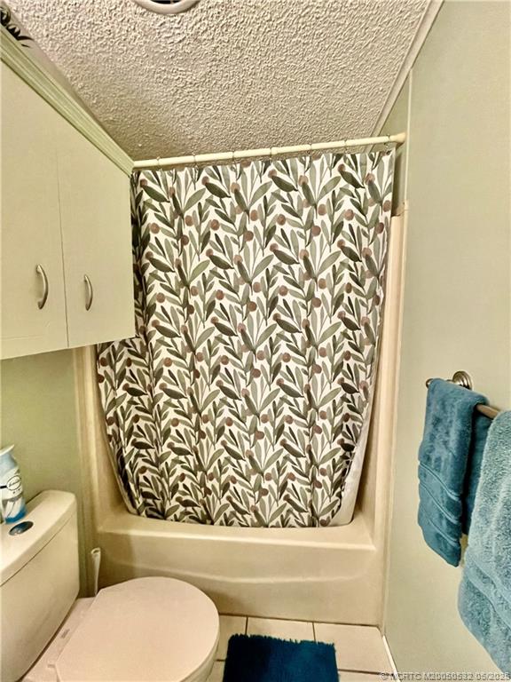 16446 Southwest Three Wood Way Indiantown, FL 34956 - Photo 24 of 32 a bathroom with a toilet and a shower curtain
