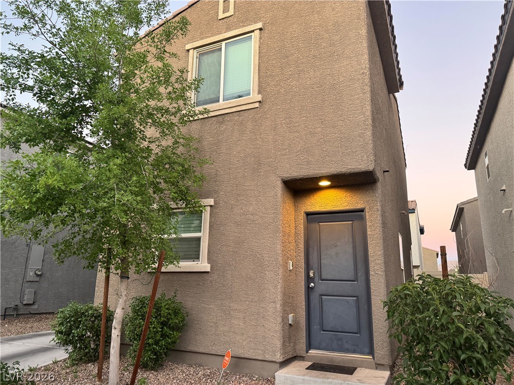 1892 Via Del Rey Court Las Vegas, NV 89115 - Photo 1 of 10 A welcoming front entrance features a dark door and stucco exterior, set against a verdant tree and clear sky.