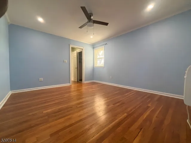 an empty room with wooden floor and ceiling fan