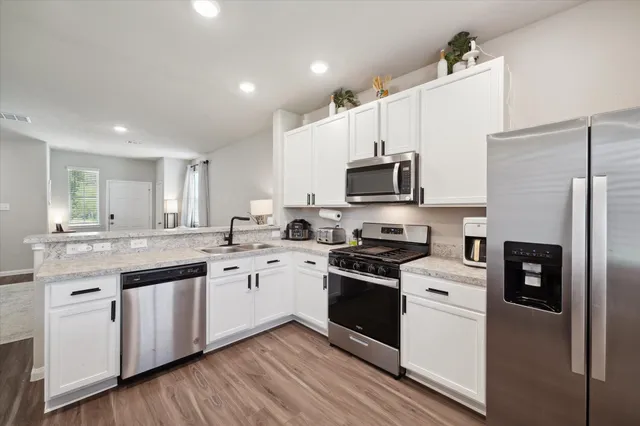 a kitchen with kitchen island granite countertop white cabinets and white appliances