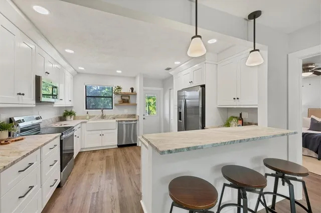 a large kitchen with kitchen island a large island a sink stainless steel appliances and cabinets