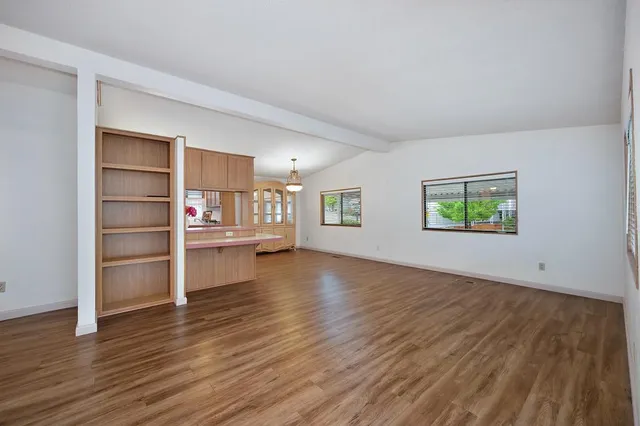 an empty room with wooden floor and window