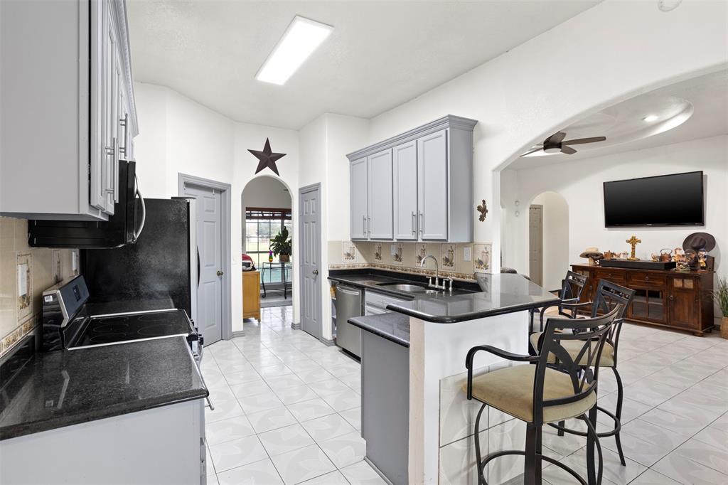 6524 Fair Road Kaufman, TX 75142 - Photo 12 of 30 a kitchen with granite countertop a stove a sink and a refrigerator