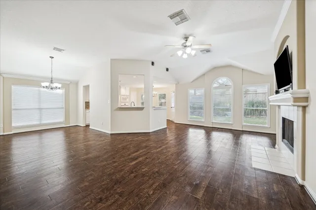 a view of an empty room with wooden floor and a fireplace