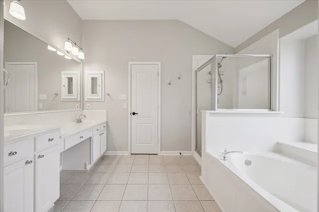 a spacious bathroom with a tub sink shower and mirror