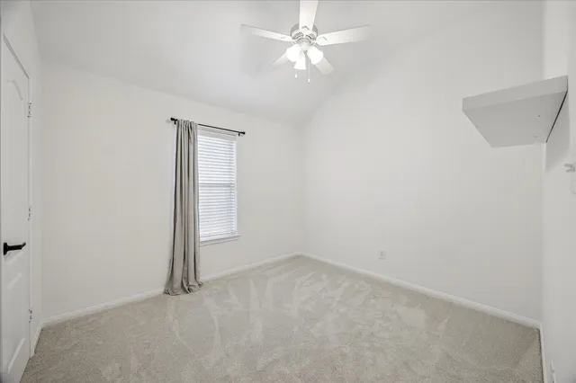 an empty room with a fan & a window