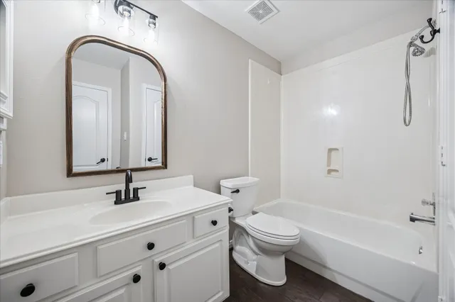 a bathroom with a toilet a sink a mirror a bathtub and vanity