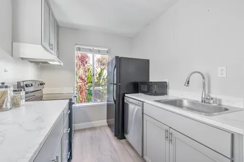 a kitchen with a sink dishwasher a refrigerator and cabinets with wooden floor