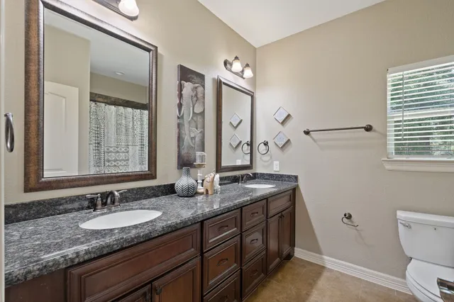 a bathroom with a granite countertop sink double vanity and a mirror
