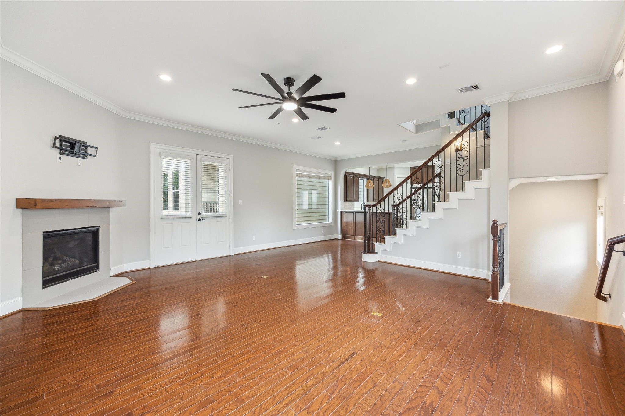 1512 Thompson Street, Unit 3 Houston, TX 77007 - Photo 8 of 32 This spacious living area features hardwood floors, a cozy corner fireplace, and a modern ceiling fan. The room is well-lit with recessed lighting and has a stylish open staircase with wrought iron railing. French doors provide stylish natural light.